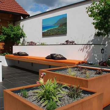 Garten Lounge mit bepflanzten Kübeln, Sitzbank und Feuerstelle