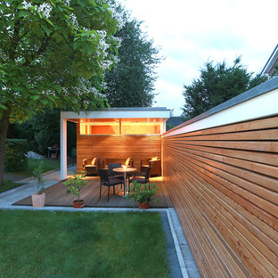 Mittelgroße, Überdachte Moderne Terrasse hinter dem Haus mit Kübelpflanzen in Sonstige