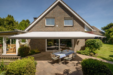 This is an example of a medium sized traditional side terrace in Essen with an awning.