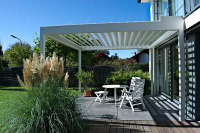 Ejemplo de terraza contemporánea pequeña en anexo de casas y patio lateral con jardín de macetas