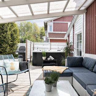 Minimalistisk inredning av en stor terrass på baksidan av huset, med en pergola