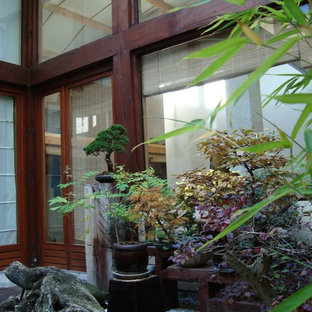 Immagine di un grande patio o portico etnico in cortile con un giardino in vaso, ghiaia e un tetto a sbalzo