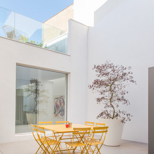 Inspiration pour une terrasse minimaliste de taille moyenne avec une cour, du carrelage et aucune couverture.