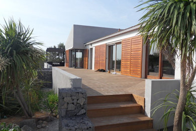 Réalisation d'une terrasse en bois arrière design de taille moyenne avec une extension de toiture.