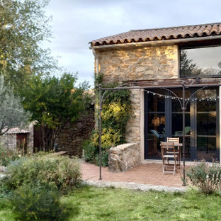 Foto di un patio o portico country di medie dimensioni e dietro casa con piastrelle e una pergola