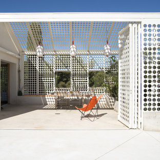 Cette image montre une terrasse latérale design de taille moyenne avec une dalle de béton et une pergola.