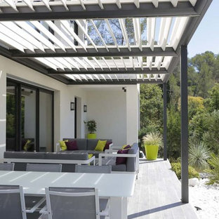 Immagine di un patio o portico design davanti casa con un giardino in vaso, graniglia di granito e una pergola