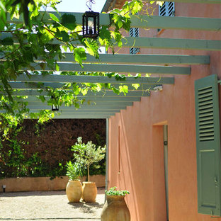 Réalisation d'une terrasse avec des plantes en pots avant méditerranéenne de taille moyenne avec du gravier et une pergola.