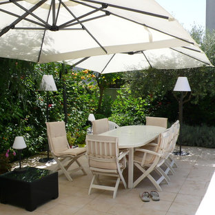 Esempio di un grande patio o portico minimal dietro casa con piastrelle e un parasole