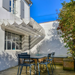 Idée de décoration pour une terrasse arrière marine de taille moyenne avec un auvent.