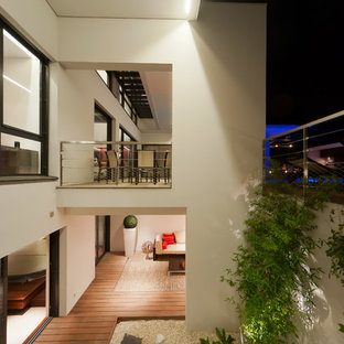 Inspiration pour une grande terrasse arrière design avec une terrasse en bois et une extension de toiture.