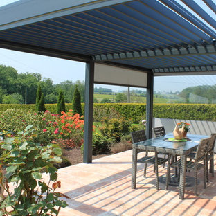 Cette photo montre une terrasse tendance de taille moyenne avec du carrelage et une pergola.