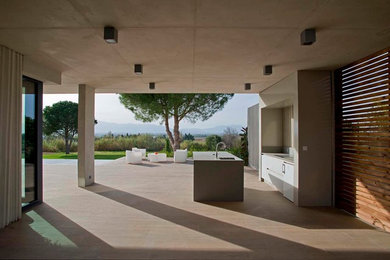 Idée de décoration pour une terrasse design avec une cuisine d'été, du carrelage et une extension de toiture.
