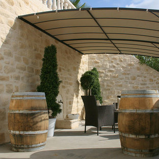 Idées déco pour une terrasse avec des plantes en pots méditerranéenne avec une dalle de béton et un auvent.