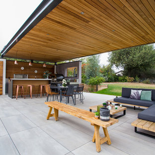 Cette photo montre une terrasse avec une cuisine extérieure arrière tendance de taille moyenne avec du carrelage et une pergola.