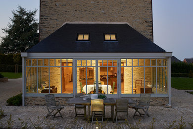 Cette image montre une grande terrasse latérale traditionnelle avec un foyer extérieur, des pavés en brique et une extension de toiture.