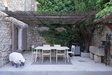 Cette photo montre une terrasse méditerranéenne de taille moyenne avec une cuisine d'été, une cour, une dalle de béton et une pergola.