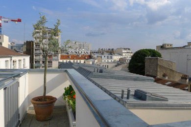 Unbedeckter Moderner Patio mit Betonplatten und Kübelpflanzen in Paris