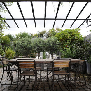 Idée de décoration pour une grande terrasse arrière tradition avec des pavés en béton et une pergola.
