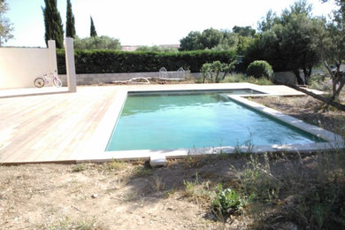 Ejemplo de piscina mediterránea de tamaño medio en patio trasero con entablado