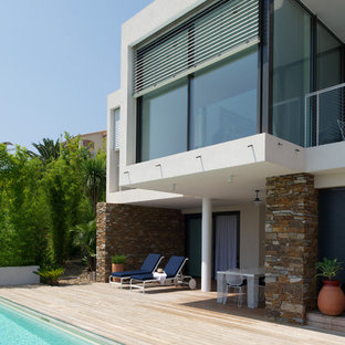 Réalisation d'une terrasse arrière design de taille moyenne avec une extension de toiture.