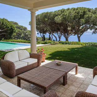 Exemple d'une terrasse avec des plantes en pots arrière chic de taille moyenne avec une extension de toiture et des pavés en pierre naturelle.