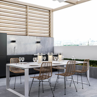 Inspiration for a large modern courtyard outdoor kitchen deck remodel in Valencia with a pergola