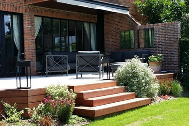 Ejemplo de terraza clásica renovada de tamaño medio en patio trasero con toldo
