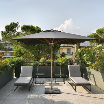 Terrazzo tematico grigio con fioriere, ombrellone e lettini
