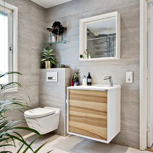 Cette image montre un WC et toilettes ethnique de taille moyenne avec un WC suspendu, un mur blanc, un sol en bois brun et un lavabo suspendu.