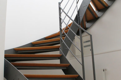 Diseño de escalera curva contemporánea extra grande con escalones de madera y barandilla de metal