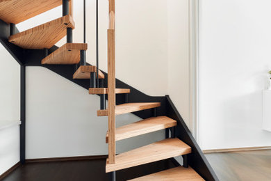 На фото: изогнутая лестница среднего размера в современном стиле с деревянными ступенями, деревянными перилами и обоями на стенах с
