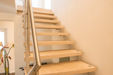 Mittelgroße Moderne Treppe in L-Form mit gebeizten Holz-Treppenstufen und Stahlgeländer in Hamburg