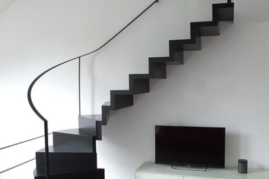 Foto de escalera curva minimalista pequeña con barandilla de metal, escalones de madera y contrahuellas de madera