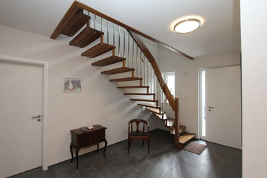 Diseño de escalera curva actual de tamaño medio sin contrahuella con escalones de madera y barandilla de varios materiales