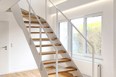 Idée de décoration pour un escalier courbe minimaliste avec des marches en bois et un garde-corps en métal.