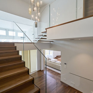 Mittelgroße Moderne Treppe in U-Form mit gebeizten Holz-Treppenstufen, gebeizten Holz-Setzstufen und Glasgeländer in München