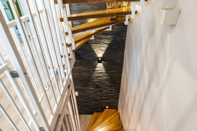 Foto de escalera de tamaño medio sin contrahuella con escalones de madera y barandilla de metal
