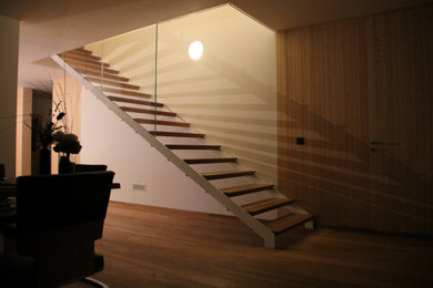 Diseño de escalera recta actual de tamaño medio sin contrahuella con escalones de madera y barandilla de vidrio
