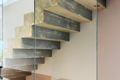 シュトゥットガルトにあるお手頃価格の広いコンテンポラリースタイルのおしゃれな直階段 (コンクリートの蹴込み板、ガラスフェンス) の写真