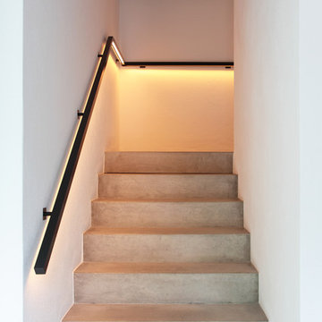 Sichtbetontreppe mit beleuchtetem Handlauf