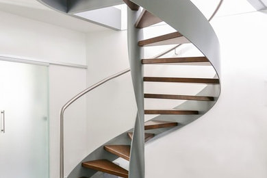 Imagen de escalera de caracol actual sin contrahuella con escalones de madera y barandilla de metal