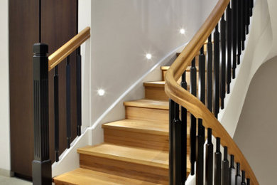 Ejemplo de escalera curva clásica con escalones de madera, contrahuellas de madera y barandilla de madera