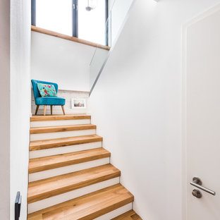 Aménagement d'un petit escalier scandinave en U avec des marches en bois et un garde-corps en verre.