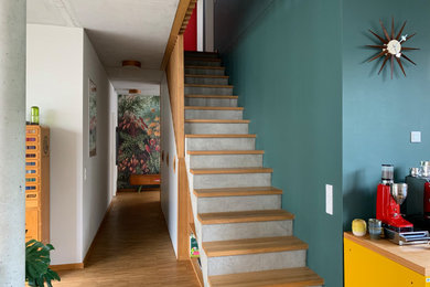 コンテンポラリースタイルのおしゃれな直階段 (コンクリートの蹴込み板、木材の手すり、壁紙) の写真