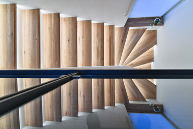 ニュルンベルクにある高級なラスティックスタイルのおしゃれなかね折れ階段 (木の蹴込み板、ガラスフェンス) の写真