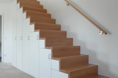 Imagen de escalera recta pequeña con escalones de madera, contrahuellas de madera y barandilla de metal