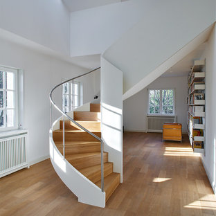 Ispirazione per una grande scala curva moderna con pedata in legno, alzata in legno e parapetto in metallo