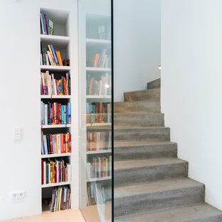 Exemple d'un escalier courbe industriel de taille moyenne avec des marches en béton, des contremarches en béton et un garde-corps en verre.