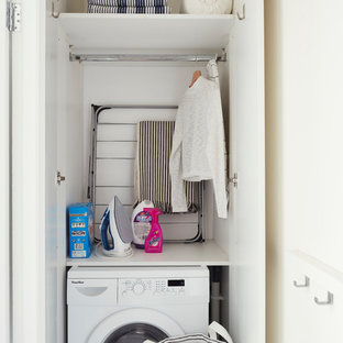 Idéer för att renovera en liten minimalistisk linjär liten tvättstuga med garderob, med släta luckor, vita skåp, vita väggar, vinylgolv och vitt golv